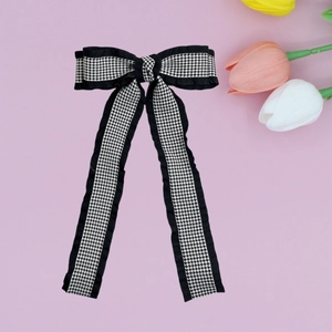 Detail of houndstooth bow hair clip with elegant long ribbons on a soft lavender background