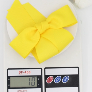 Détail d'un nœud papillon en ruban jaune vif de 10g pesé sur une balance de précision