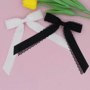 Close-up of black and white lace bow hair clips on a soft pink background