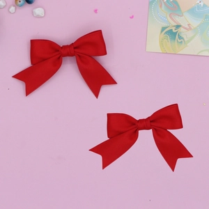 Detail view of red grosgrain ribbon swallowtail hair bows on a soft pink background