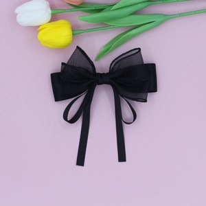 Detail of elegant black layered organza and satin bow hair clip with long ribbons