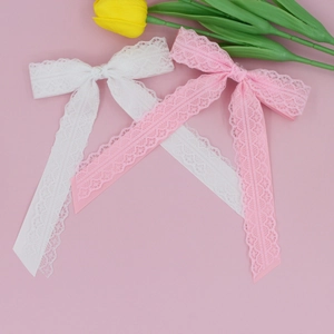 Detail of long white and pink lace bow hair clips with delicate ribbons and floral decor