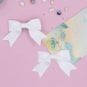 Close-up of white grosgrain ribbon swallowtail hair bows on a soft pink background