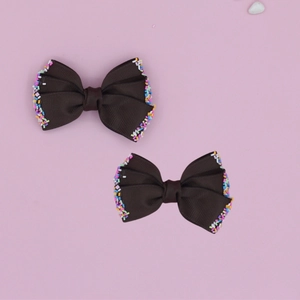 Detailed macro view of dark brown grosgrain ribbon hair bow clips with colorful sprinkles