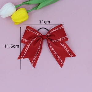 Detail view of 11cm red ribbon bow hair clip with white wavy edges on a pink background