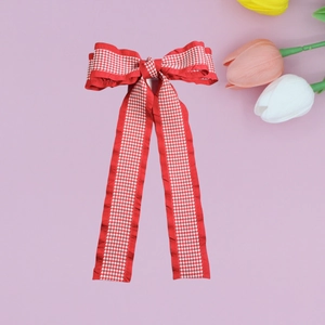 Detail of red and white houndstooth bow hair clip with long elegant ribbons on purple background