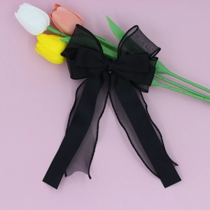 Détail d'un nœud papillon noir multicouche en organza et satin sur une surface rose