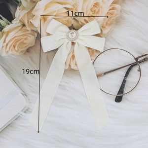 Elegant cream velvet bow hair clip with golden rose emblem and pearl trim details