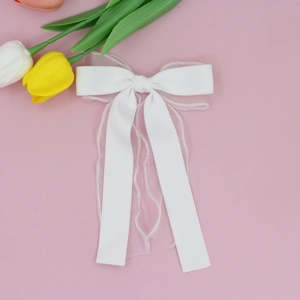 Détail de la barrette à double nœud en tulle blanc avec rubans élégants en satin
