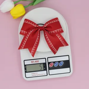 Detail showing red grosgrain ribbon bow hair clip with white dotted wavy patterns