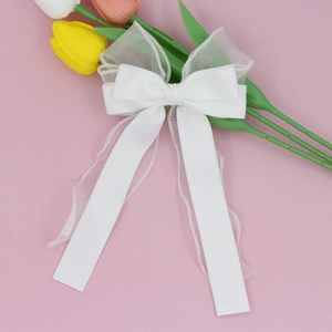 Détail d'un nœud papillon en organza blanc multicouche avec de longs rubans fluides