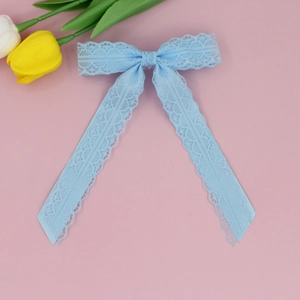 Detail of light blue lace bow hair clip with ribbons on elegant floral background
