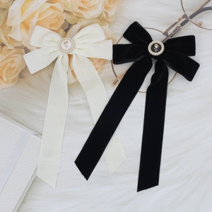 Detail of velvet bow hair clips with pearl rose metal buckles in black and cream