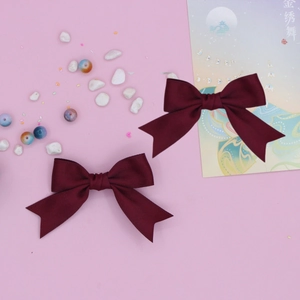 Detailed close-up of wine red swallowtail bow hair clips with textured grosgrain fabric
