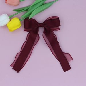 Détail de la pince à cheveux bordeaux avec double nœud en résille et satin élégant