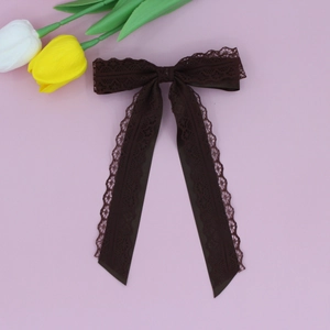 Detail of the elegant dark brown lace bow hair clip with decorative satin ribbons