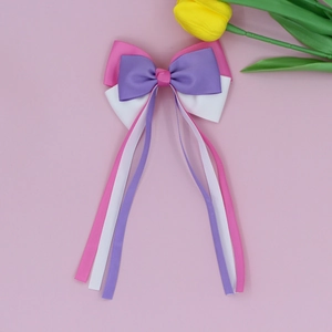 Close-up of tricolor ribbed ribbon bow hair clips with long streamers on pink background