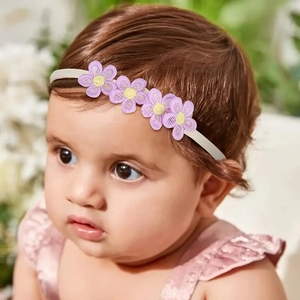 Elastic baby headband with four purple lace flowers shown on infant model with soft lighting
