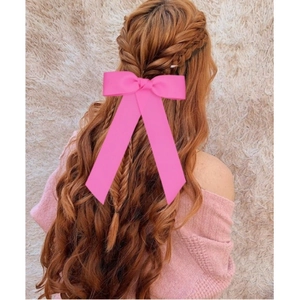 Vue de dos d'une pince à cheveux à long ruban rose portée sur des cheveux bouclés