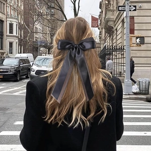 Double-layered black silk bow hair clip with long ribbons shown on a half-up hairstyle