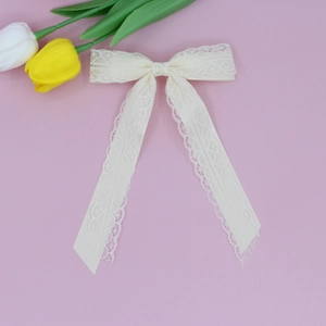 Detailed close-up of a sweet beige lace bow hair clip with elegant long ribbons