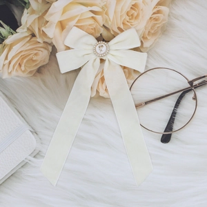Detail of cream velvet bow hair clip with vintage rose relief and pearl embellishments