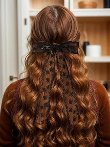 Detalle de un lazo de encaje marrón con bordado floral negro y cintas largas para el pelo