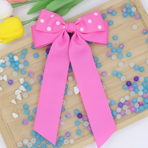 Dettaglio del fermaglio per capelli in nastro rosa a pois con lunghi nastri