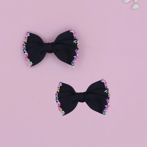 Detail of black ribbed ribbon bow hair clips with colorful sprinkle edge decorations
