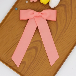 Détail du nœud papillon en ruban rose avec de longs rubans sur un plateau en bois
