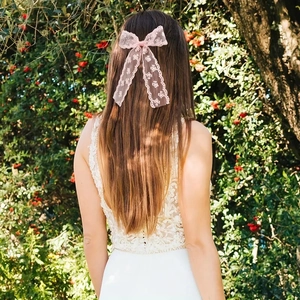 Detalle de lazo de encaje rosa con cintas largas para el pelo sobre cabello largo