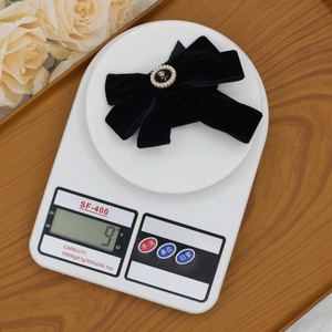 Detail view of black velvet bow hair clip with pearl rose button weighing only 9g