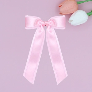 Detail of a light pink satin double-layered bow hair clip with a smooth glossy texture
