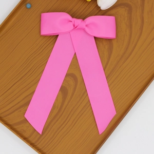 Détail d'un nœud papillon rose vif en ruban gros-grain avec rubans sur un plateau en bois