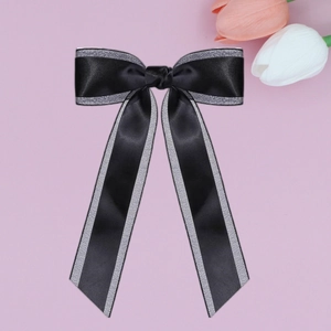 Detail of double-layer black satin bow hair clip with silver glitter edge and long ribbons