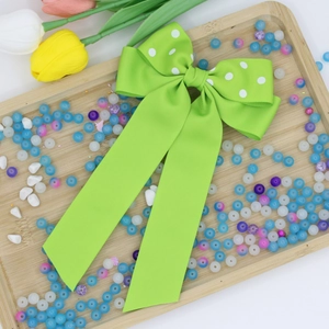 Dettaglio del fiocco in gros-grain verde erba con pois bianchi e lunghi nastri sottili