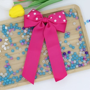 Dettaglio di un grande fiocco in gros-grain fucsia a pois con lunghe code fluenti in seta