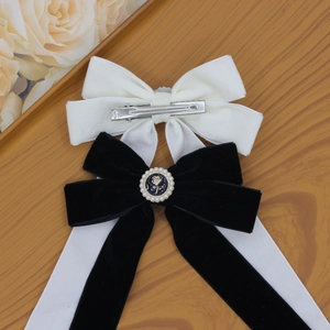 Vintage velvet bow hair clips in black and white with rose charms on wood background
