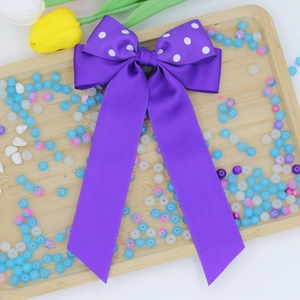 Dettaglio di un fermaglio per capelli a fiocco viola a pois con lunghi nastri eleganti