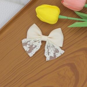 Detailed macro view of cream lace bow hair clip featuring ribbed fabric and soft layering