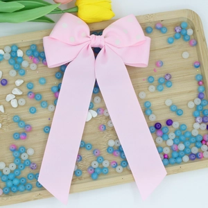Vista dettagliata del fermaglio per capelli con fiocco rosa a pois in grosgrain