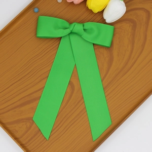 Détail d'un nœud papillon vert en ruban côtelé avec de longs rubans sur plateau en bois