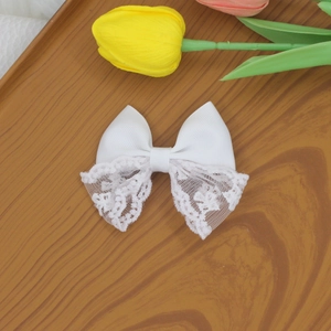 Detailed view of a sweet white lace bow hair clip featuring intricate floral embroidery