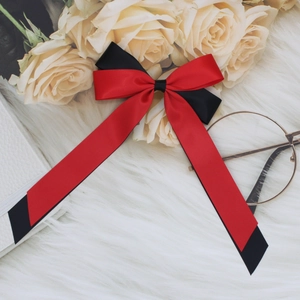 Detail shot of a red and black satin bow hair clip on a white faux fur surface