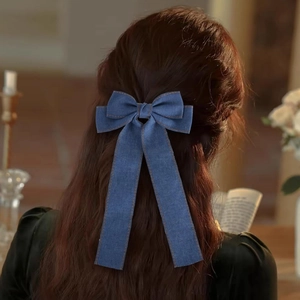 Makroaufnahme einer dunkelblauen Jeans-Haarschleife mit Kontrastnähten an den Bändern
