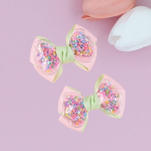 Detailed close-up of pink and mint green ribbon hair clips with sparkling star sequins