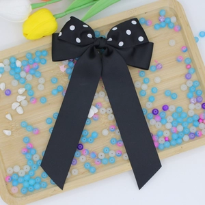 Dettaglio di un fiocco in nastro grosgrain nero con pois bianchi e lunghi nastri eleganti