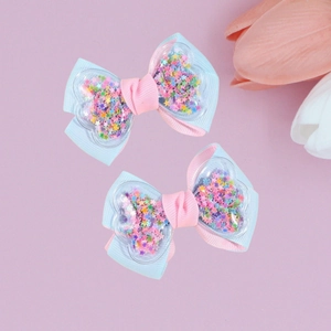 Detail of sweet bow hair clips with heart-shaped quicksand and colorful star sequins