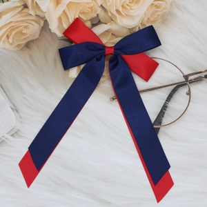 Detail of red and blue ribbon bow hair clip with long streamers on white fur background