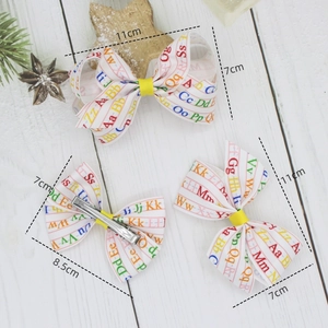 Three-piece children's bow hair clip set with colorful printed alphabet on white ribbons